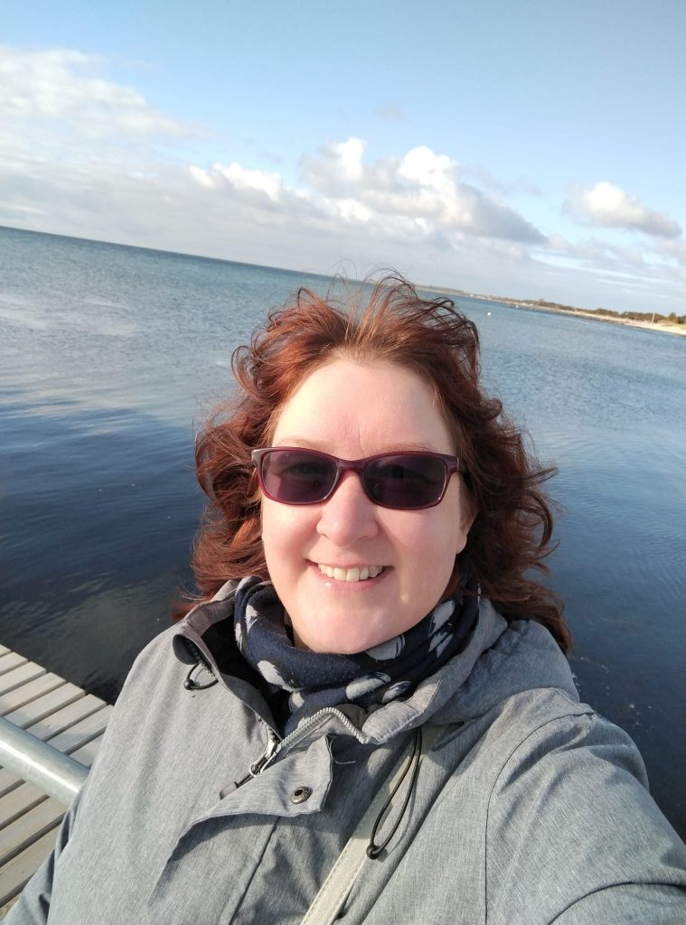 vorne Nicole Gerbatsch mit Sonnenbrille dahinter das Meer mit ein paar Wolken