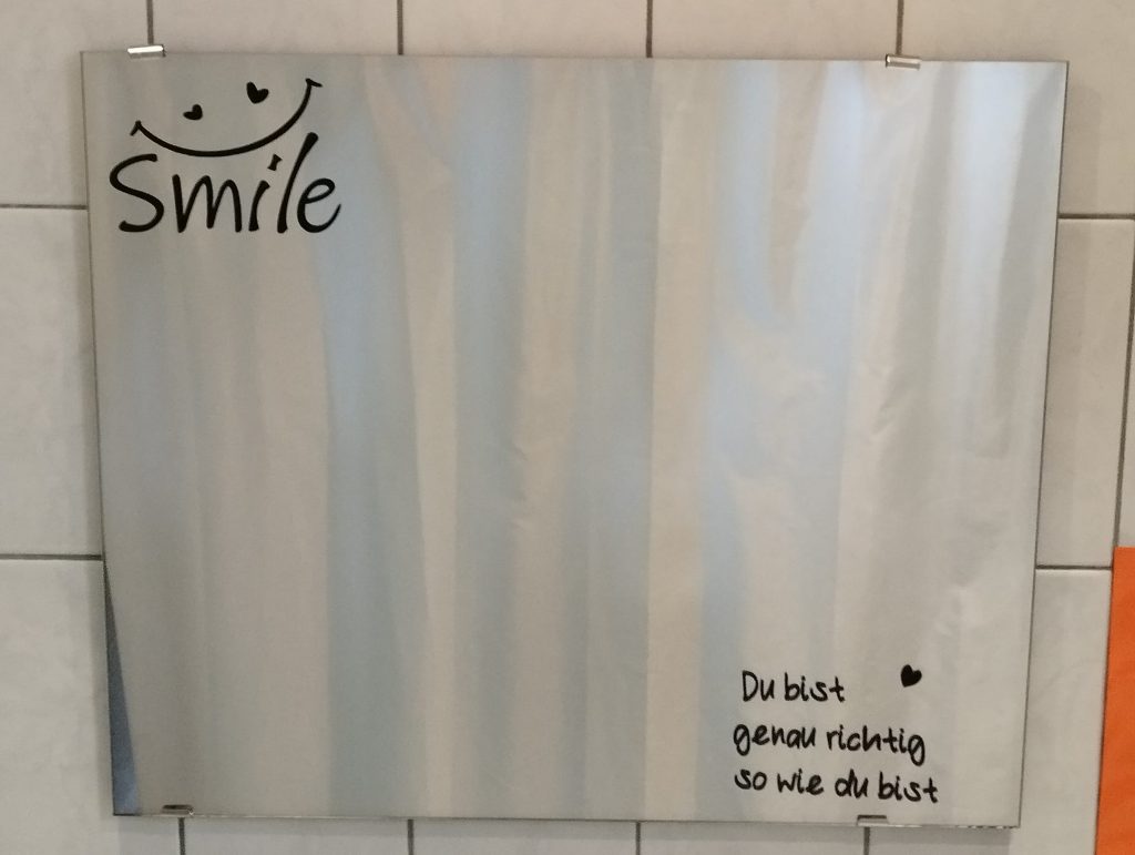 Spiegel oben links ein Aufkleber mit smile untern rechts ein Aufkleber mit 